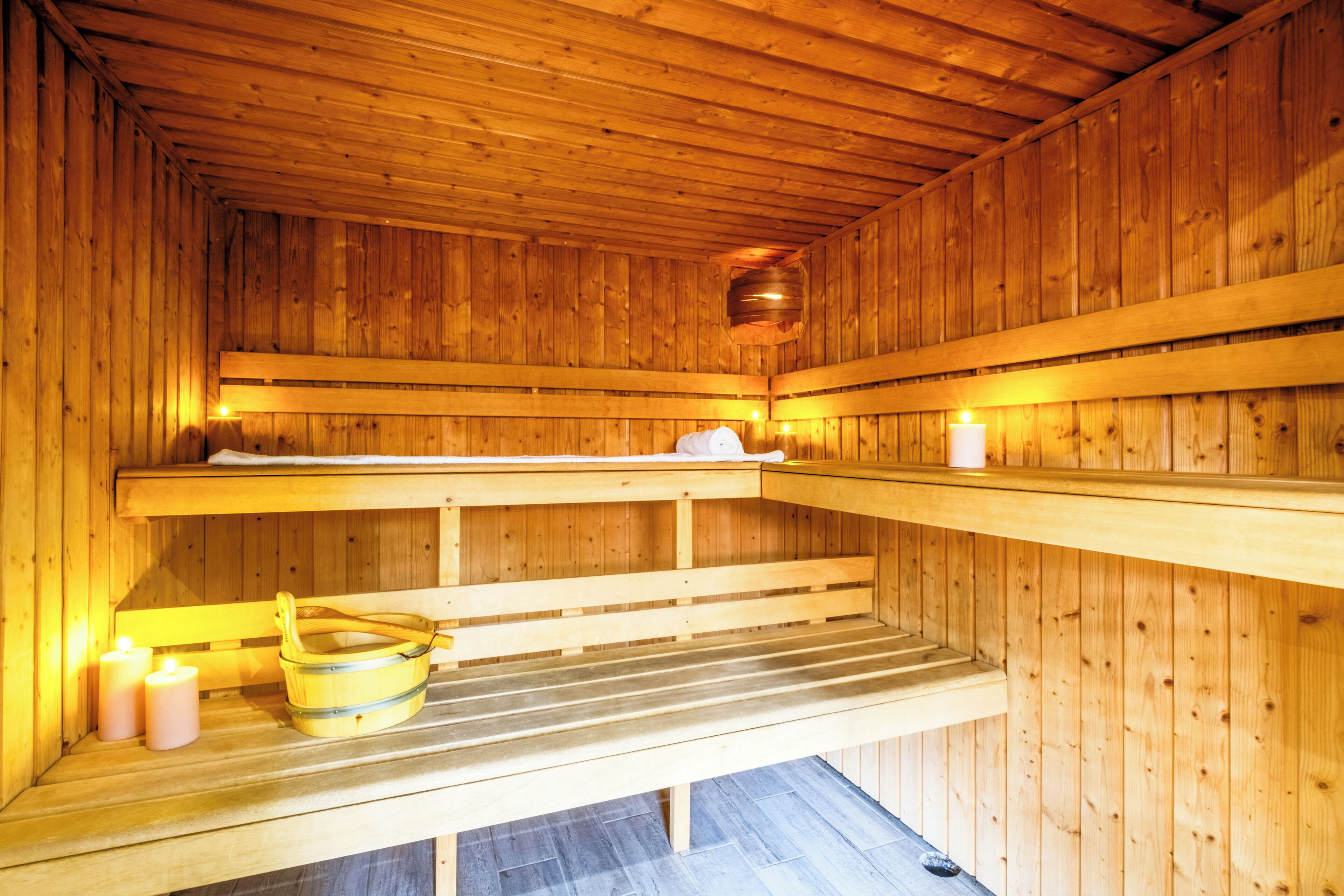 Una sauna con bancos de madera, un cubo y velas.