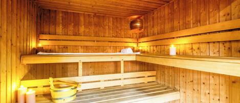 Uma sauna com bancos de madeira, um balde e velas.