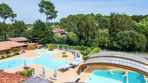 A resort with multiple swimming pools, sun loungers, and a covered area with umbrellas. - Résidence Pierre & Vacances Les Cottages du Lac (Parentis-en-Born)