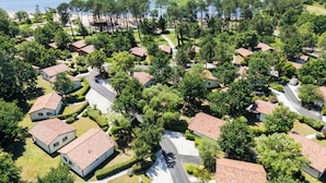 A residential area with houses, trees, and a body of water in the background. - Résidence Pierre & Vacances Les Cottages du Lac (Parentis-en-Born)