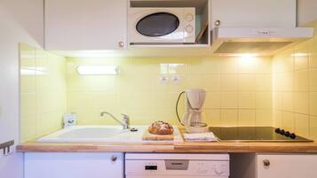 Una cocina con microondas, cafetera y una hogaza de pan sobre la encimera.