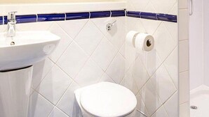 A bathroom with a white sink, toilet, and shower. - Travelodge Derby Chaddesden (Derby)