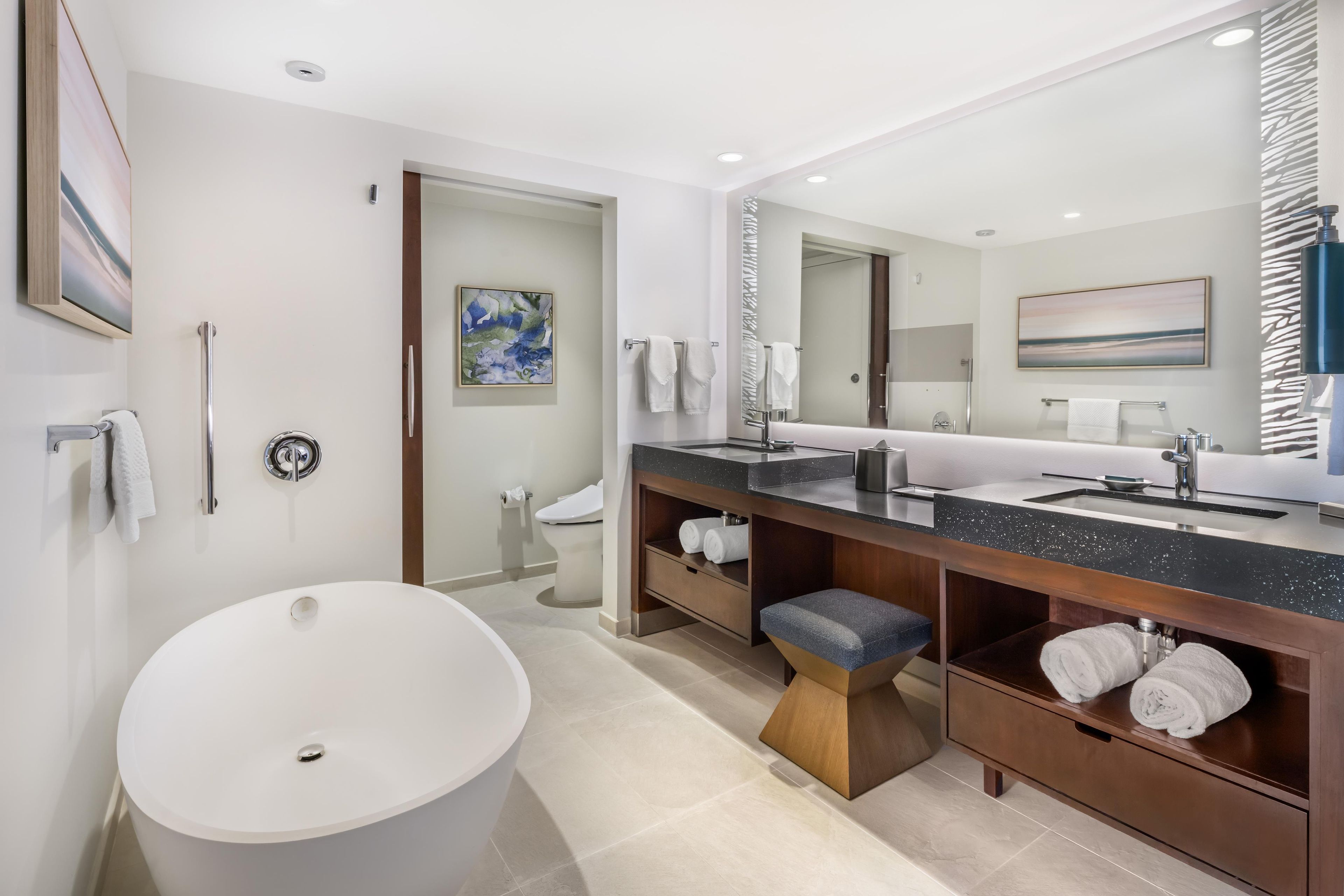 A modern bathroom with a large white bathtub, a double sink vanity, and a walk-in shower.