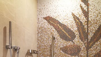 A shower area with a mosaic tile wall and a handheld showerhead.