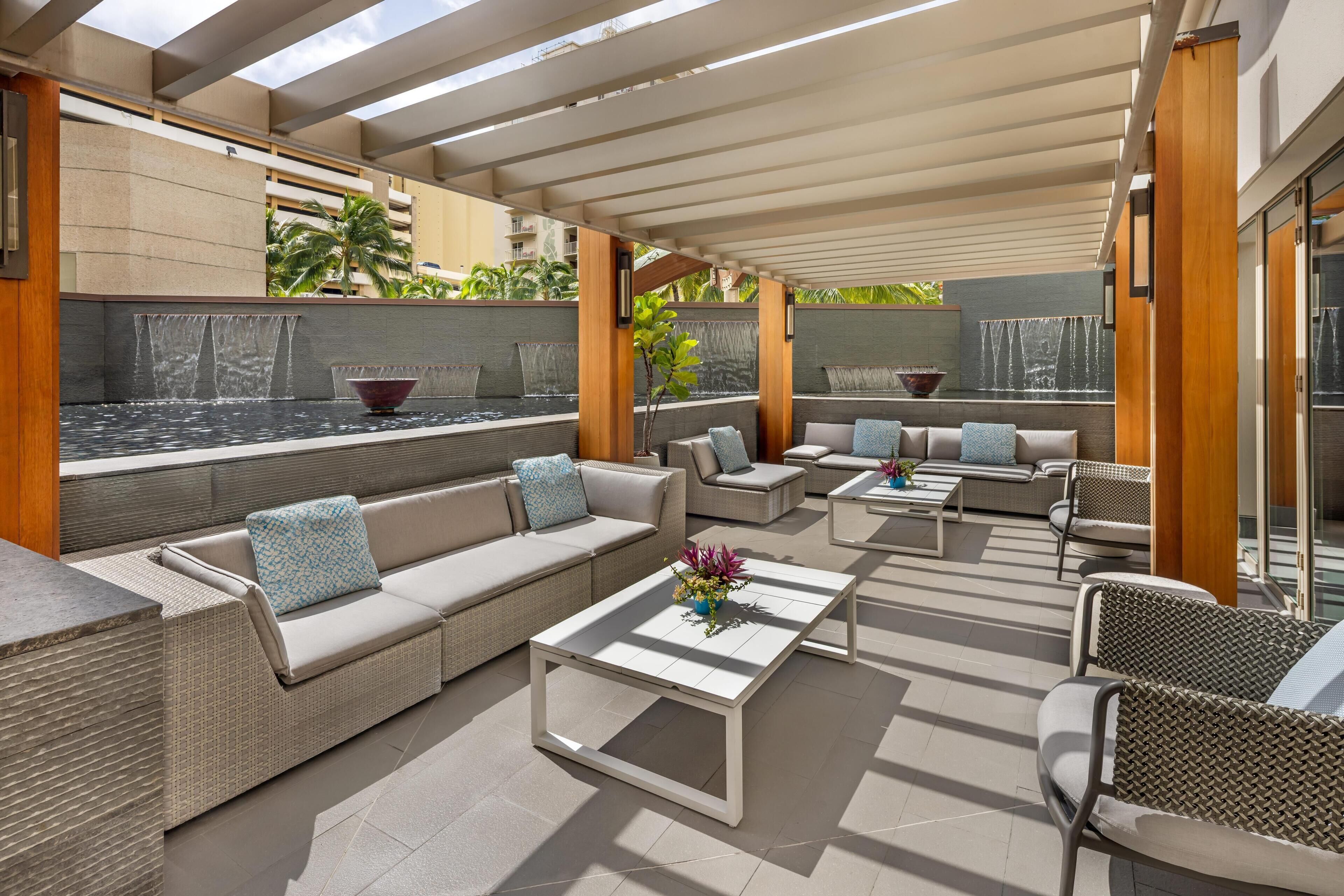 Un área de estar al aire libre con piscina, sillones de descanso y una pérgola.