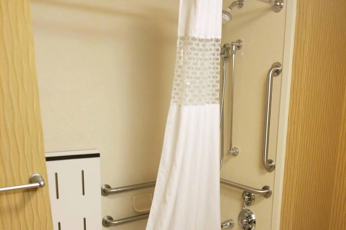 A bathroom with a bathtub, a shower with a handheld showerhead, and a toilet.