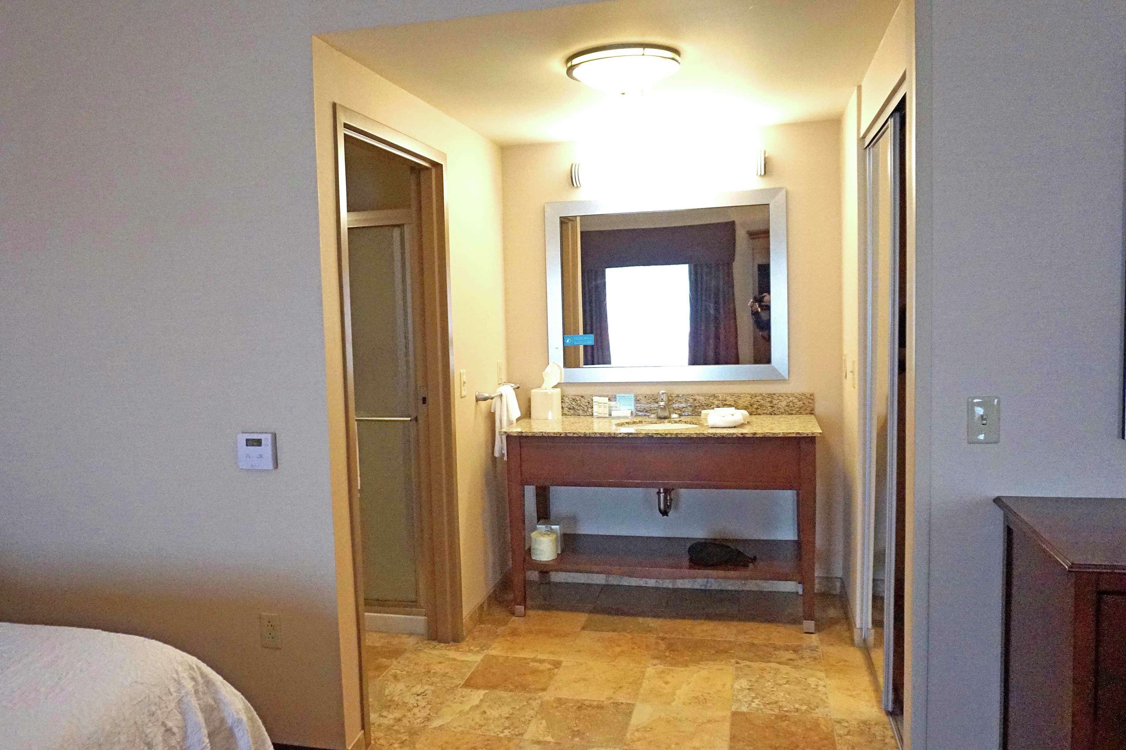 Un baño con tocador de madera, un espejo y un inodoro.