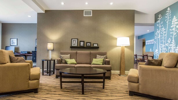 Eine moderne Hotellobby mit einer braunen Sofagarnitur, einem runden Couchtisch und einem gemusterten Teppich.
