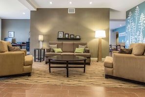 A modern hotel lobby with a brown sofa set, a round coffee table, and a patterned carpet. - Sleep Inn & Suites Clintwood (Clintwood)