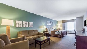 Ein Hotelzimmer mit grüner Wand, einer Couch, einem Bett, einem Schreibtisch und einer Lampe.