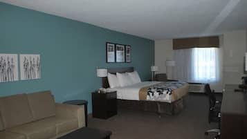 A hotel room with a bed, a desk, a chair, a sofa, and artwork on the walls.