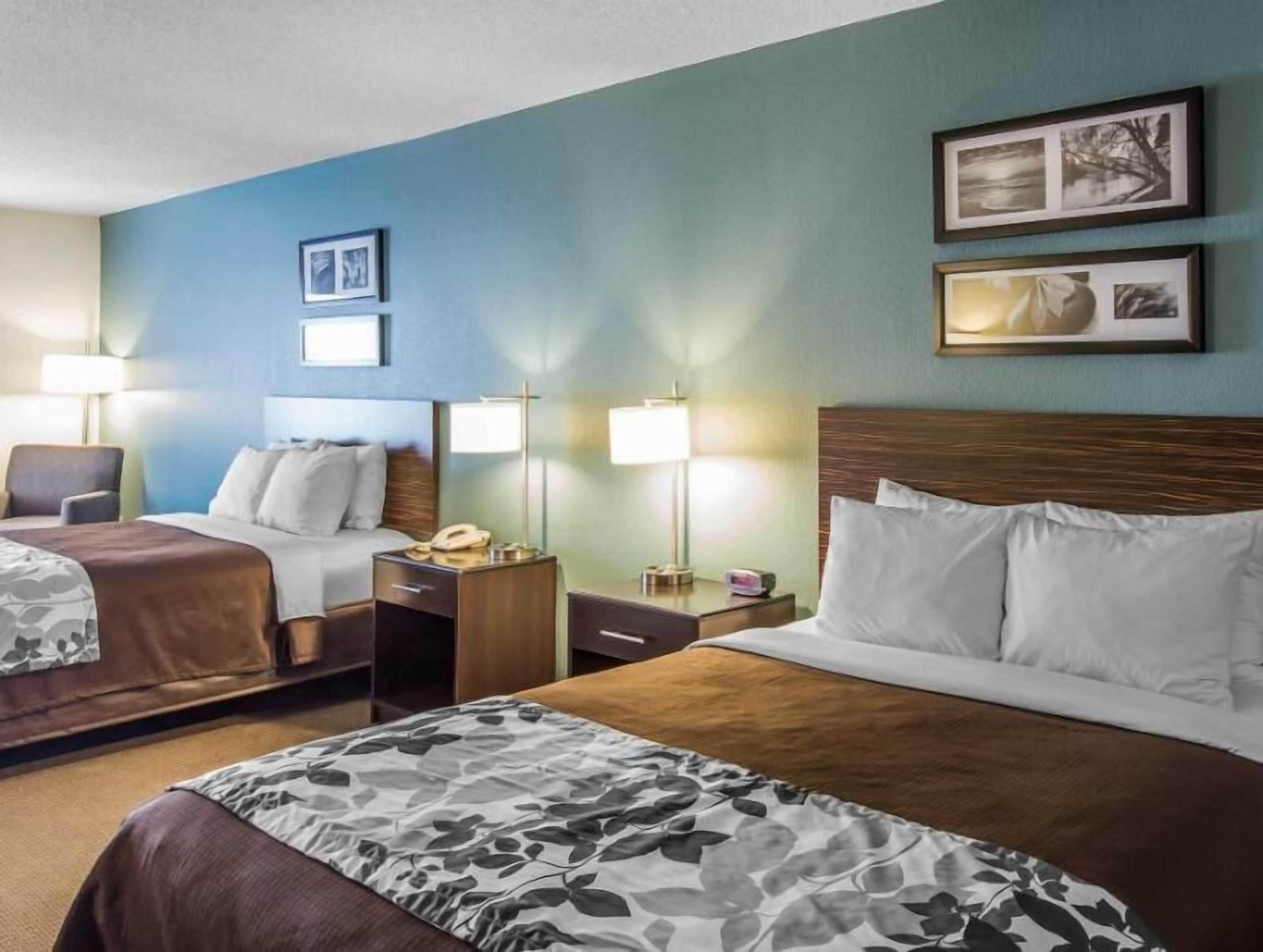 A hotel room with two beds, a desk, a chair, and two bedside lamps.