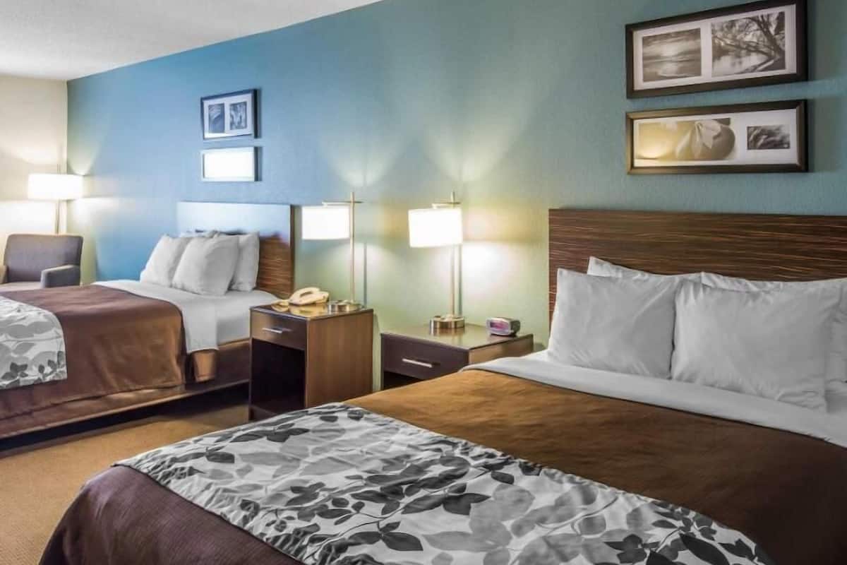 Une chambre d’hôtel avec deux lits, un bureau, une chaise et deux lampes de chevet.