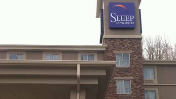 A Sleep Inn & Suites building with a stone facade, a covered entrance, and a signboard.