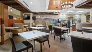 A restaurant with booths and tables, wooden ceiling, and a mountain mural.