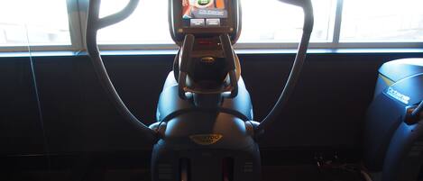 A stationary bike with a digital screen displaying a fitness program, positioned in a room with large windows.