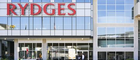 A Rydges hotel with large windows, outdoor seating, and potted plants.