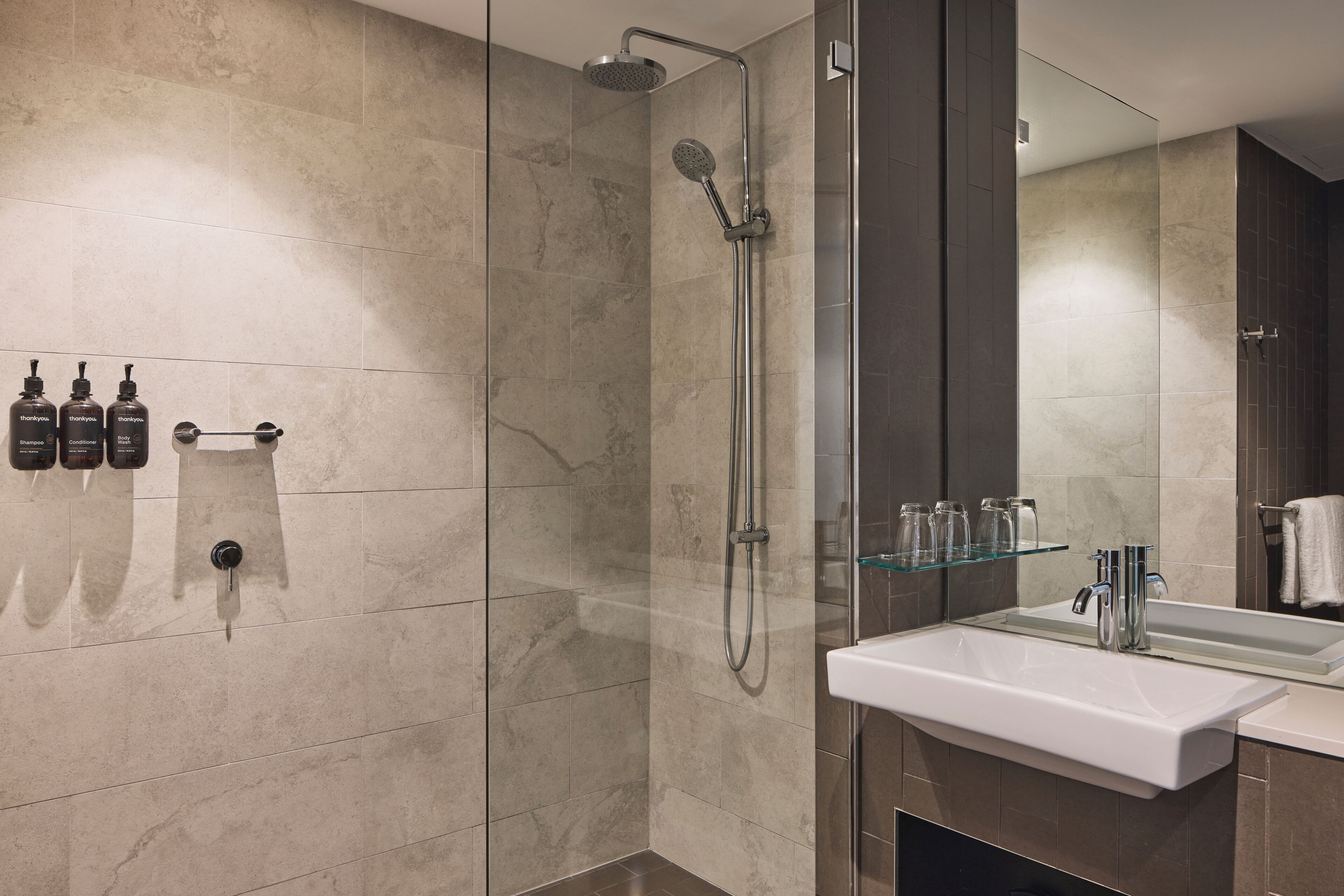A modern bathroom with a glass-enclosed shower, a white sink, and a mirror above it.