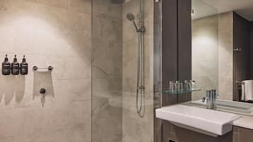 A modern bathroom with a glass-enclosed shower, a white sink, and a mirror above it.