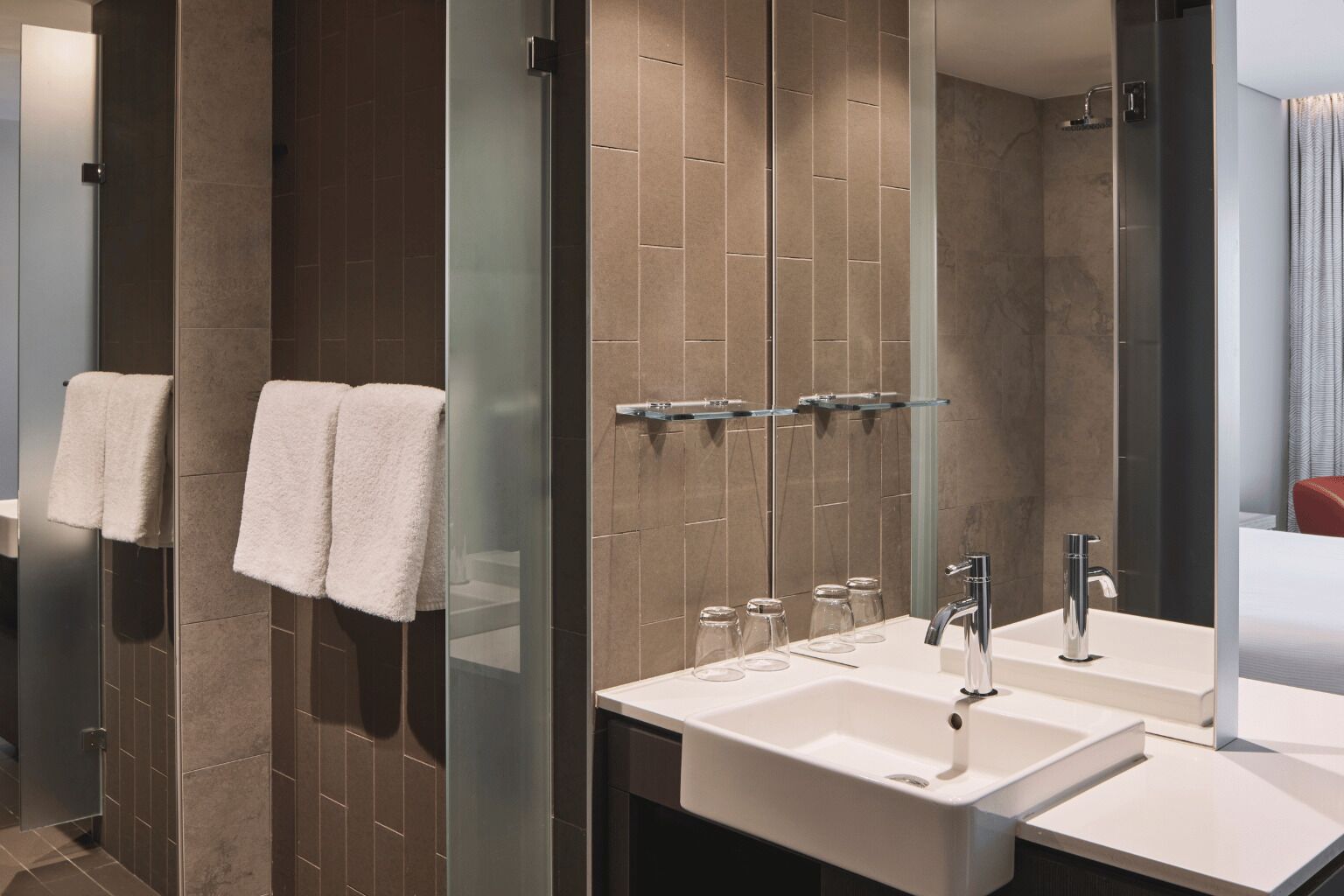 A modern bathroom with two sinks, a glass shower enclosure, and a large mirror.