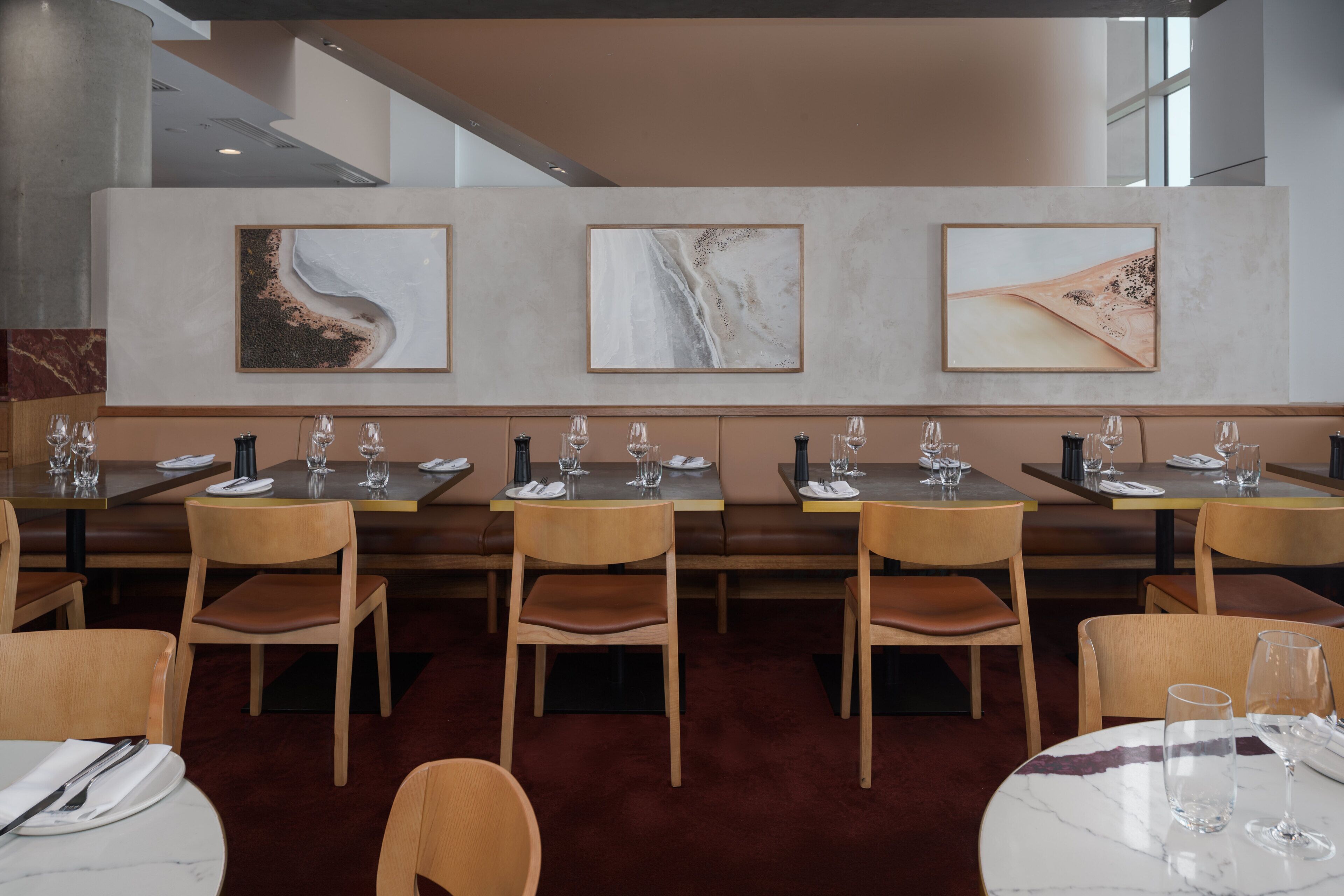 A restaurant with multiple tables and chairs, each set with plates, cutlery, and glasses.