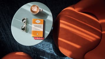 A round table with a book, a pair of sunglasses, and a cup of coffee.