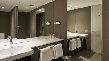 Un bagno moderno con due lavabi, uno specchio grande e un’area doccia.