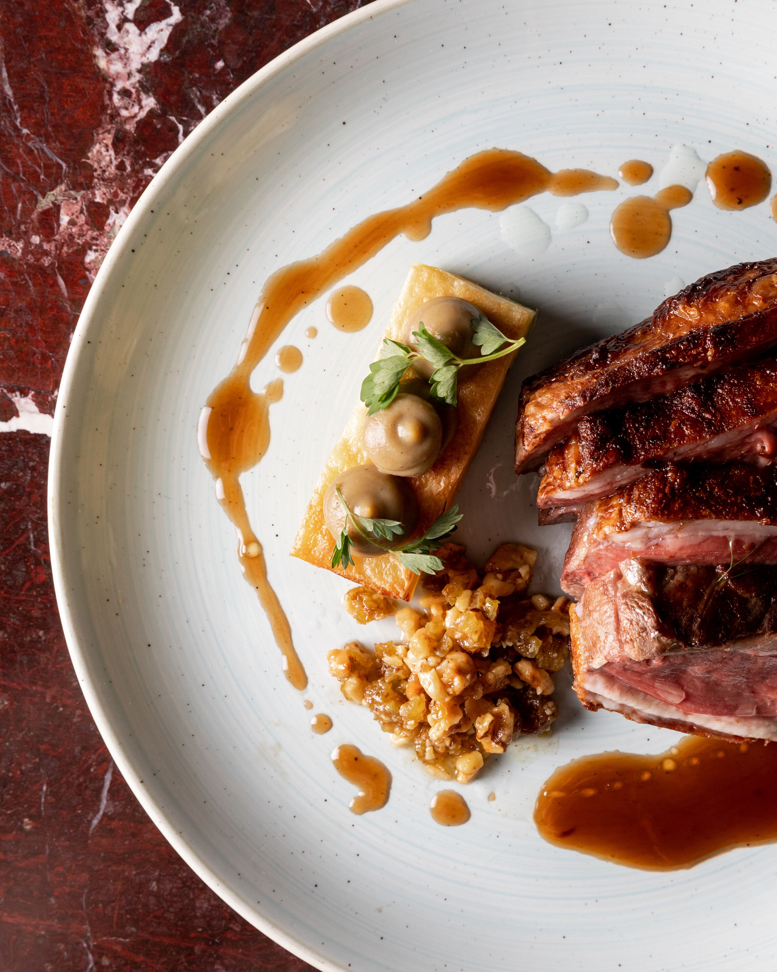 A plate with a dish consisting of meat, a sauce, and a garnish.
