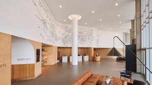 En rummelig lobby med en central søjle, en receptionsdisk og et siddeområde med sofa og stole.