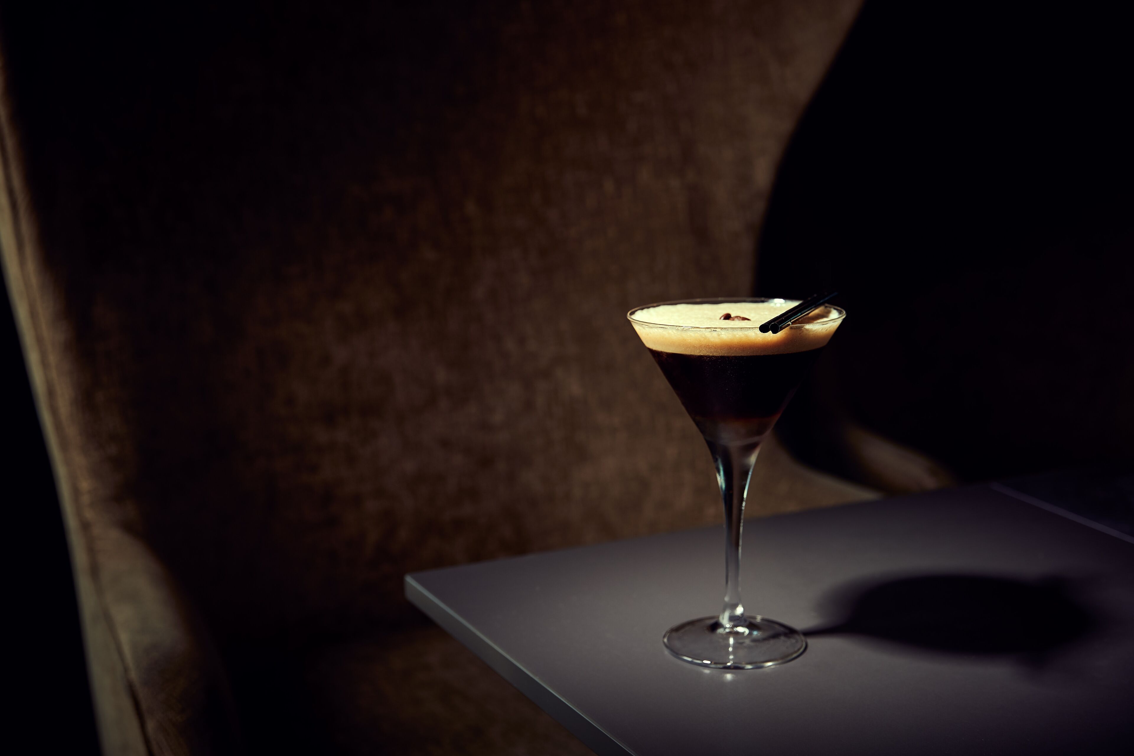 A martini glass with a frothy top on a table.