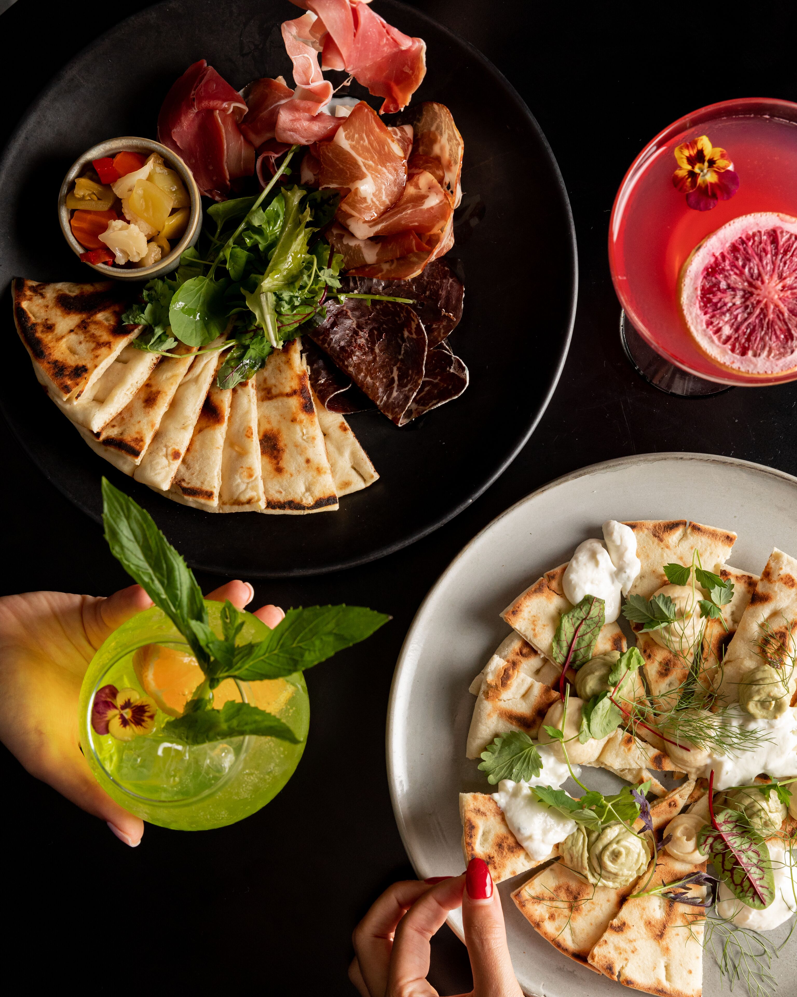 A table with various food items including grilled vegetables, meat, and a drink with a slice of grapefruit.