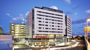 Et hotel med flere etager, et tydeligt 'RYDGES'-skilt, en parkeringskælder og et moderne arkitektonisk design.