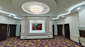 A spacious room with a patterned carpet, a central framed artwork, and a chandelier. - Safran Hotel (Baku)