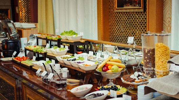 A buffet with various food items and utensils. - Safran Hotel (Baku)