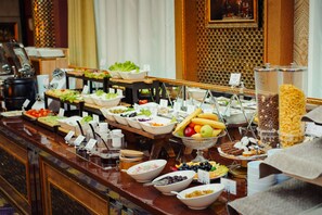 Um buffet com diversos alimentos e utensílios.