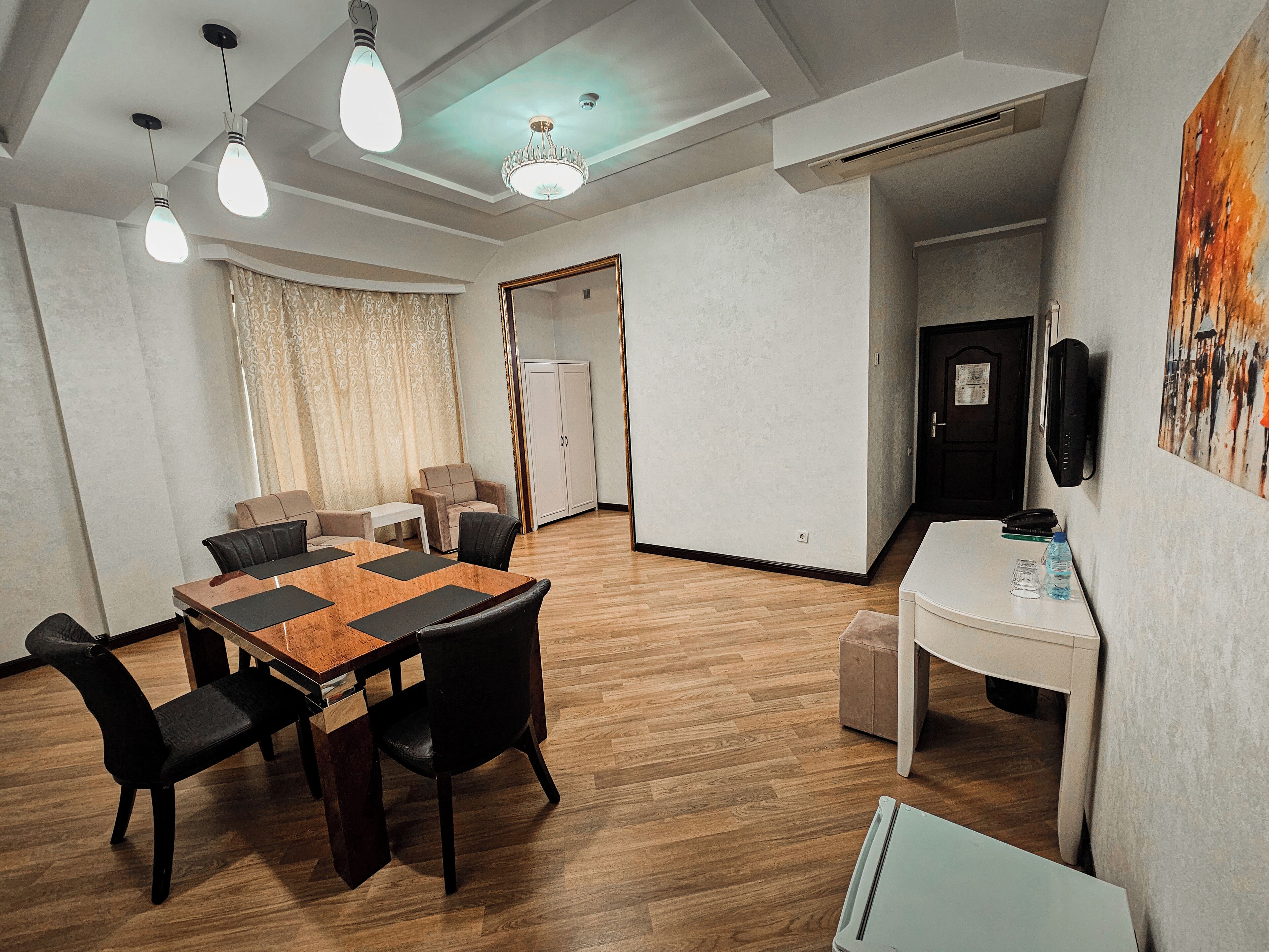 A modern conference room with a wooden table, black chairs, a chandelier, and a whiteboard.