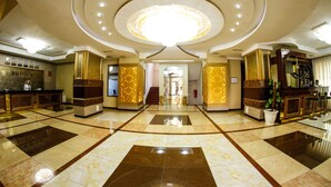 A hotel lobby with a central chandelier, reception desk, and a staircase leading to upper floors. - Safran Hotel (Baku)