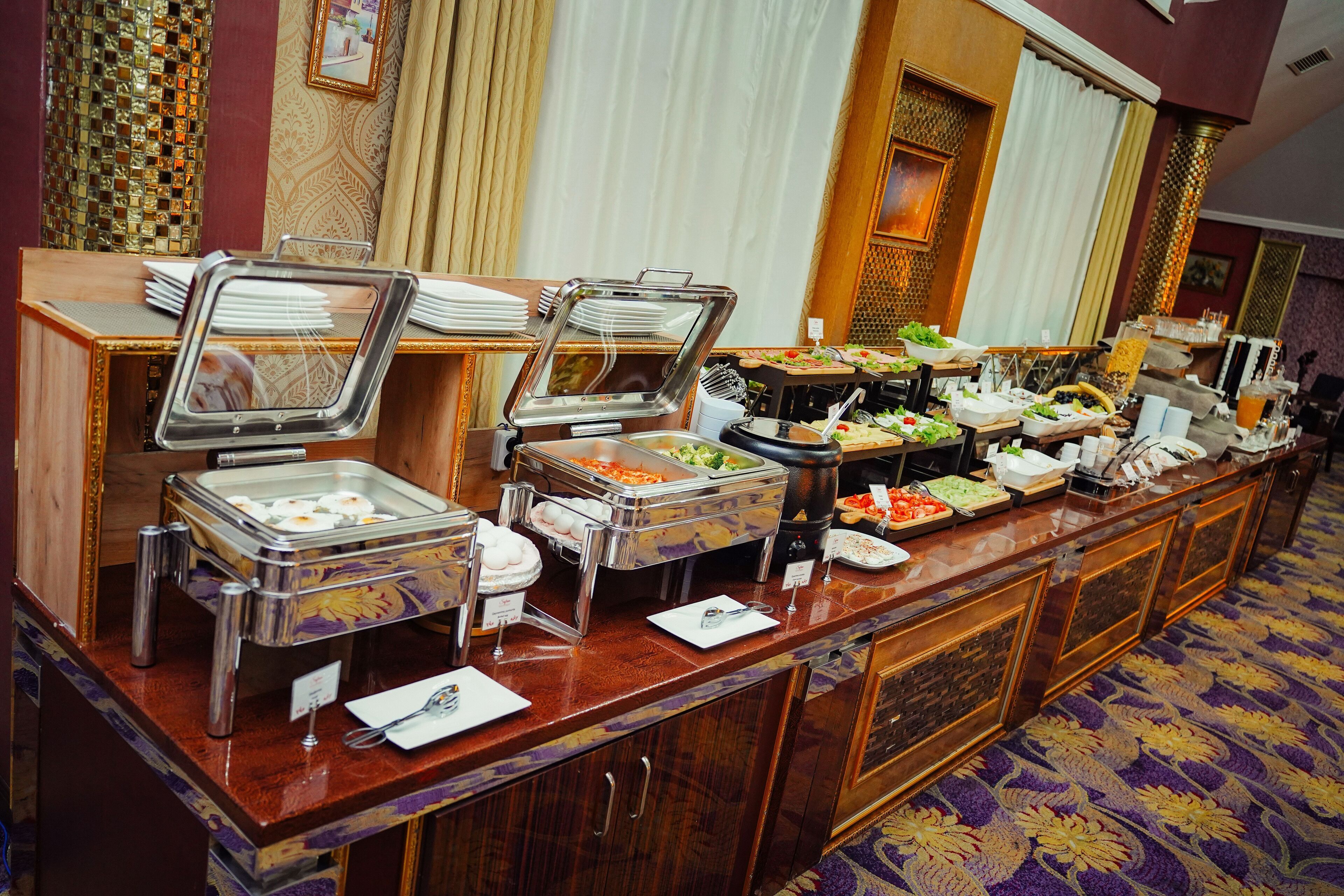 A buffet setup with various food items in glass containers, a wooden counter, and a patterned carpet.