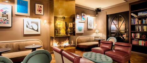 A cozy lounge area with leather sofas, a fireplace, and framed artwork on the walls.