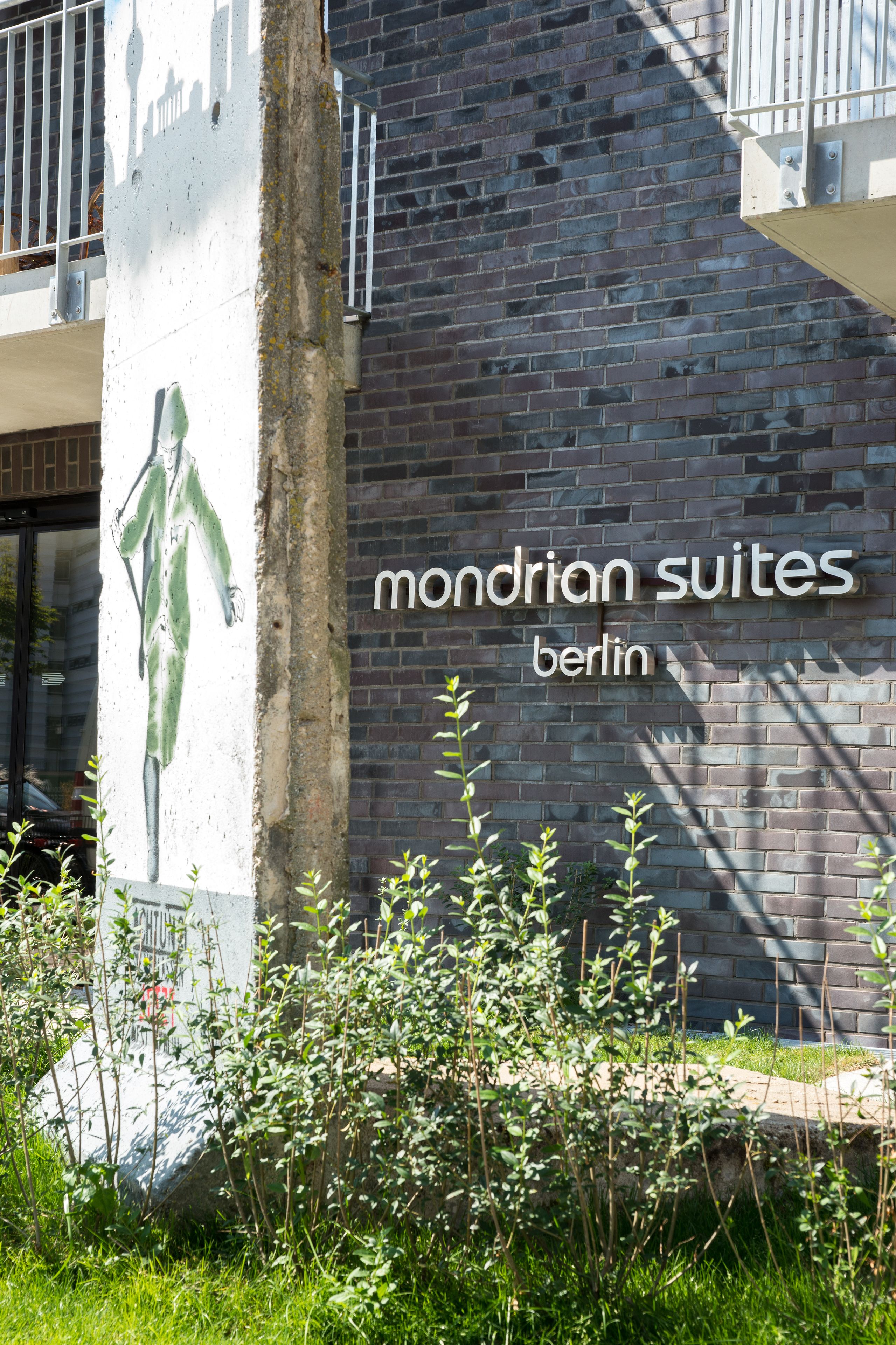A building with a sign reading "Mondrian Suites Berlin" and a mural of a figure.