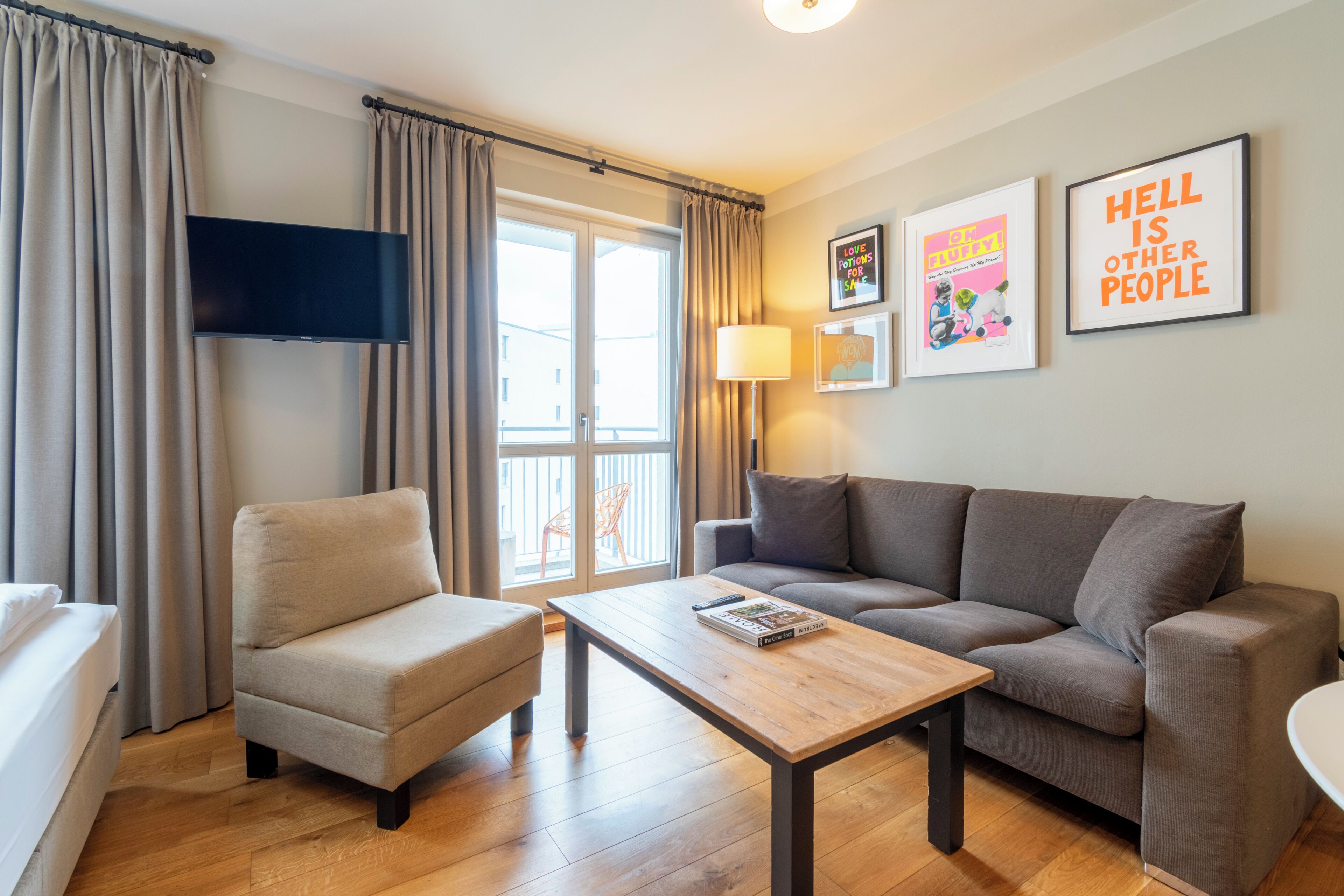 A modern living room with a sofa, armchair, and coffee table, a flat-screen TV, and two framed pictures on the wall.