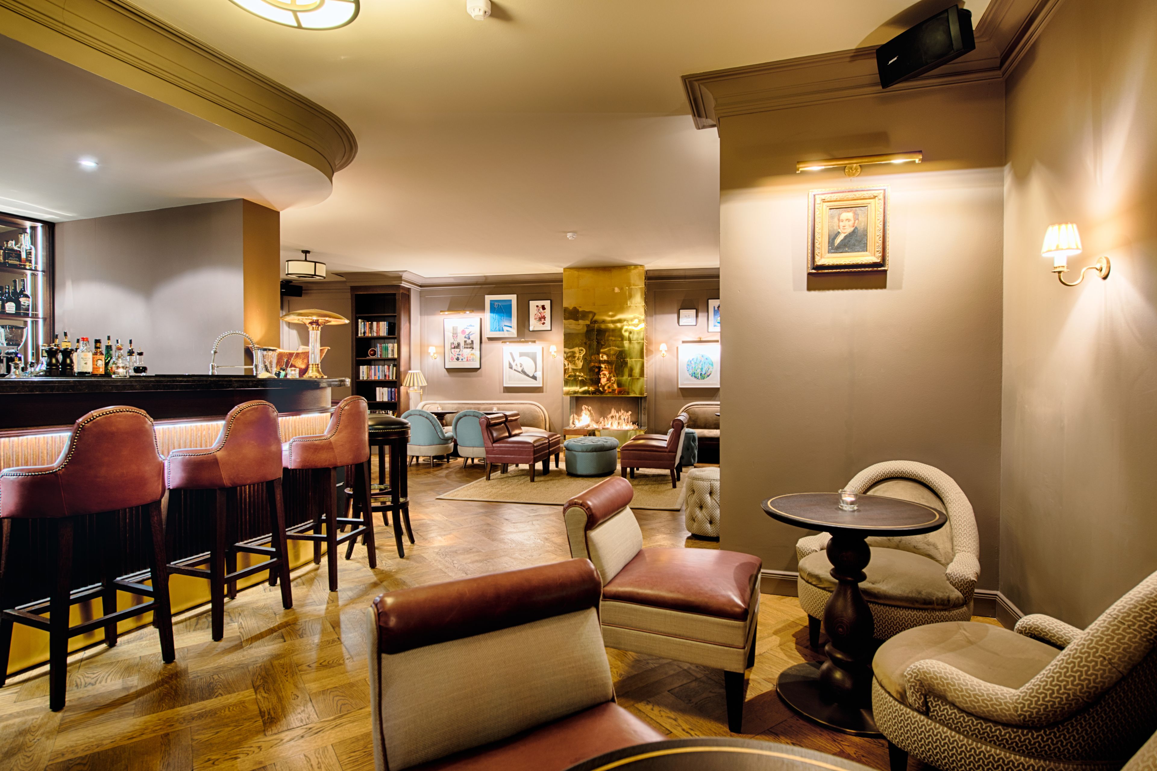 Un espace bar avec des tabourets, un comptoir et un coin salon avec des chaises et des poufs.