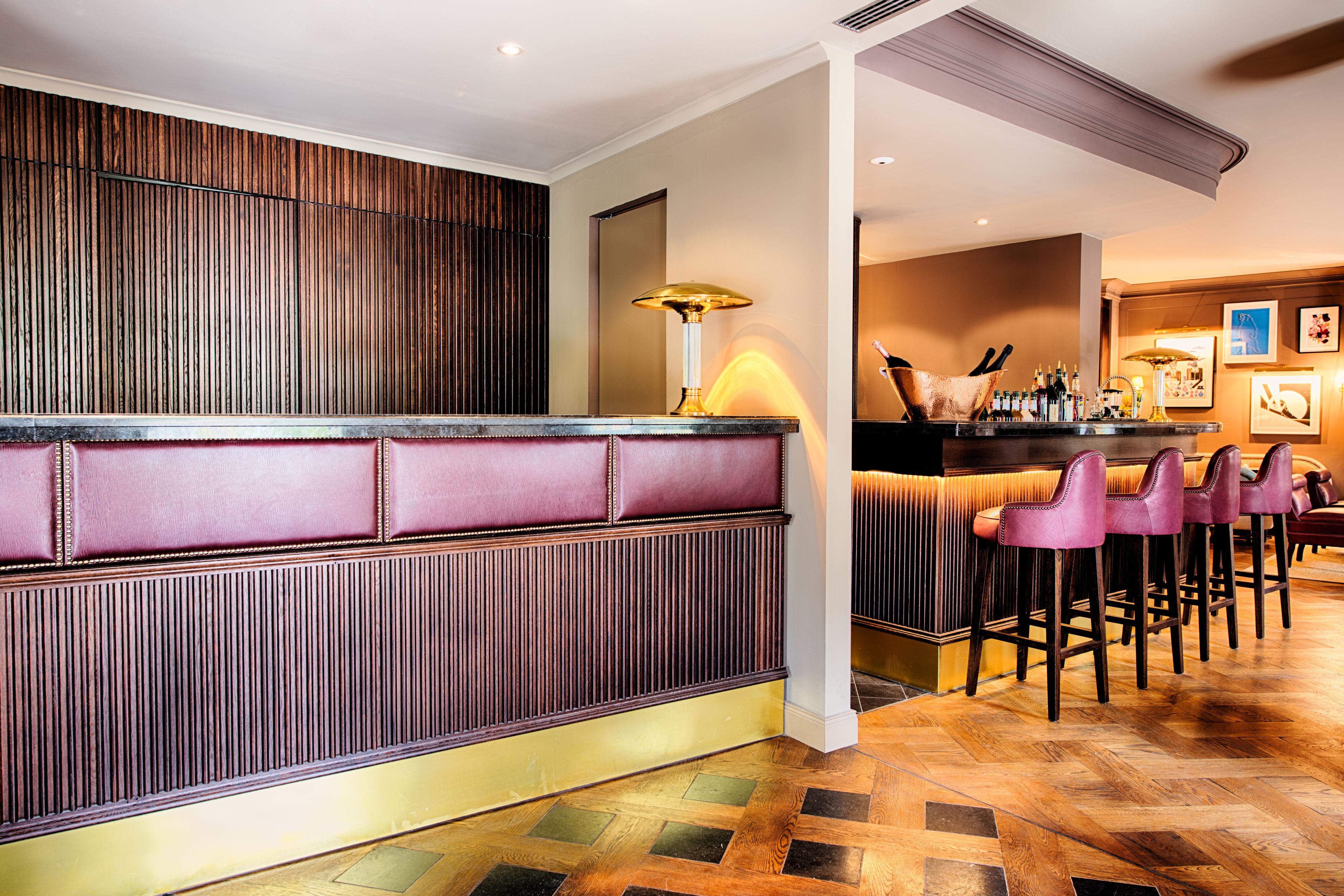 Eine Bar mit einer Holzwand, einer gepolsterten Bank und mehreren Barhocker.