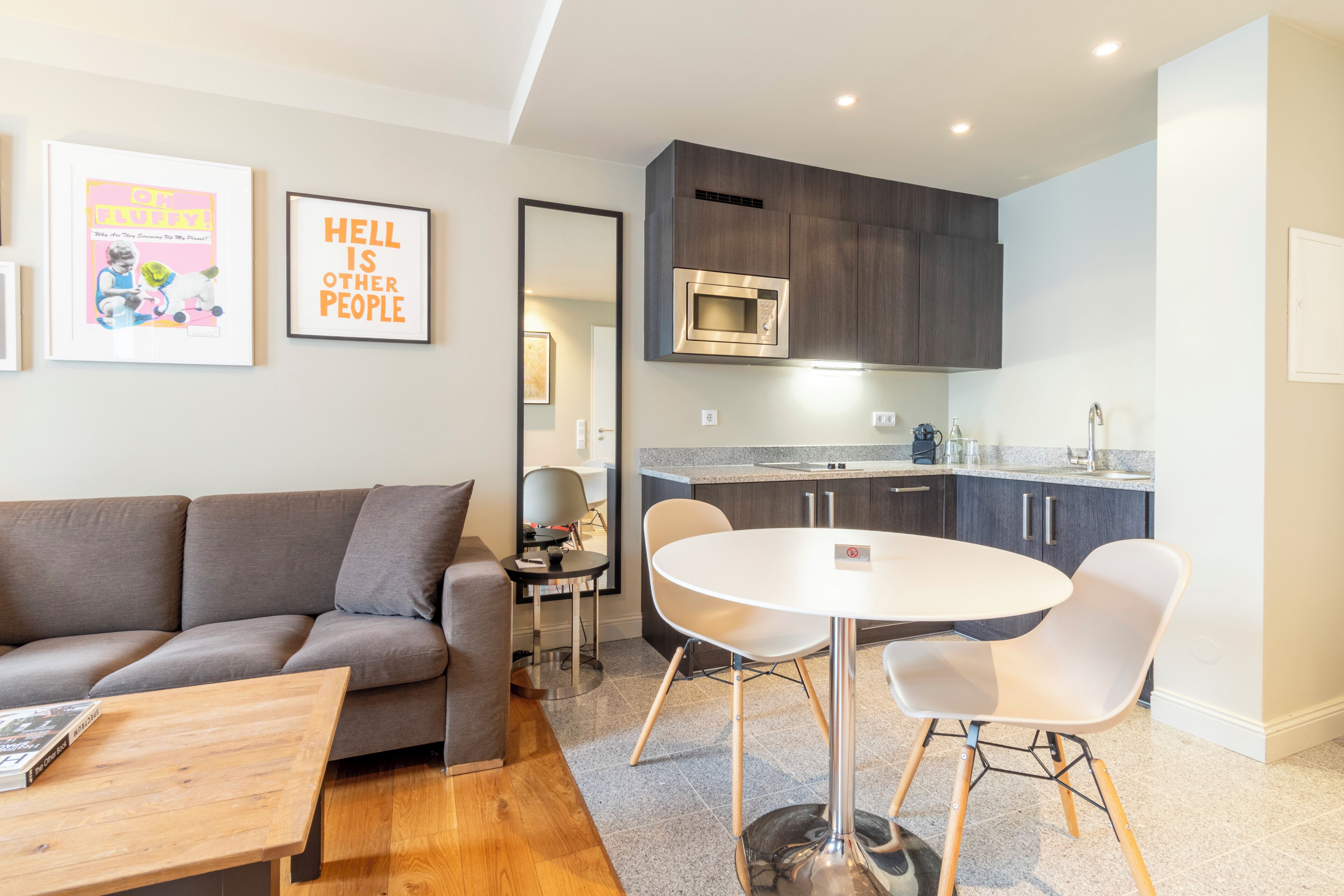 A modern living room with a grey sofa, a round white table, and a coffee table.