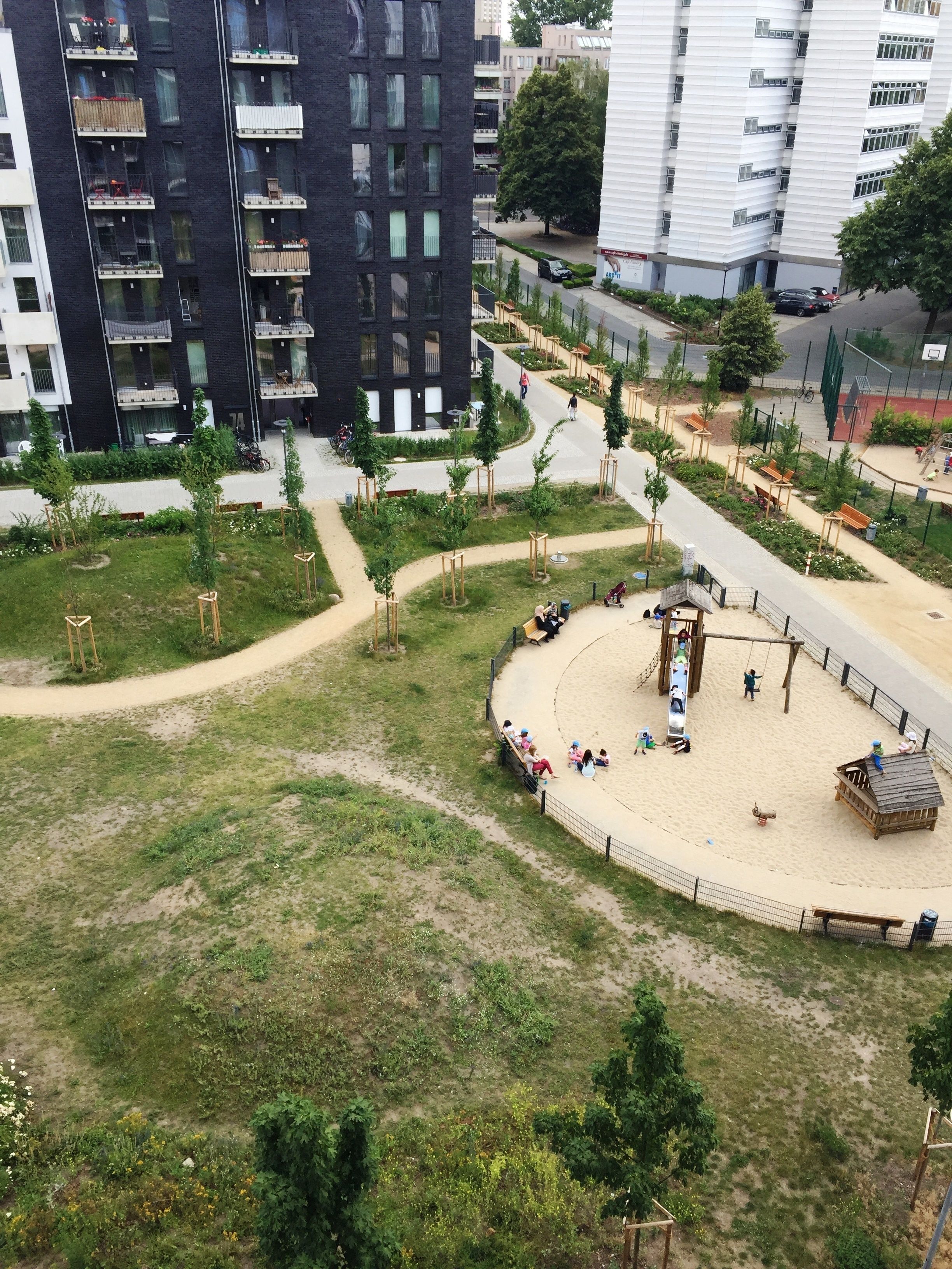 A park with a playground, benches, and a sandy area.