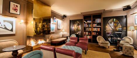 A cozy living room with a fireplace, plush seating, and a bookshelf.