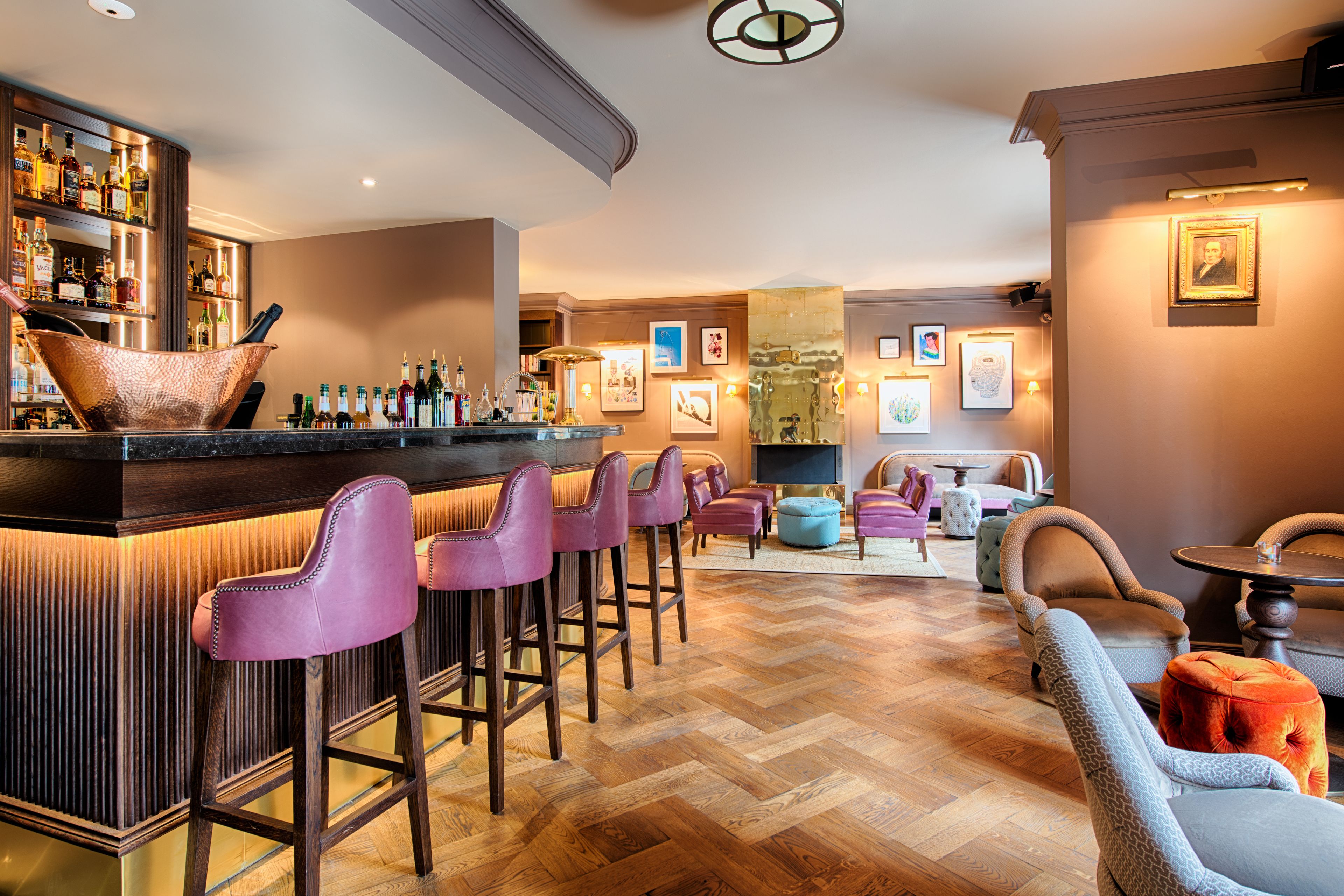 A bar area with stools, a bar counter, and a variety of bottles.