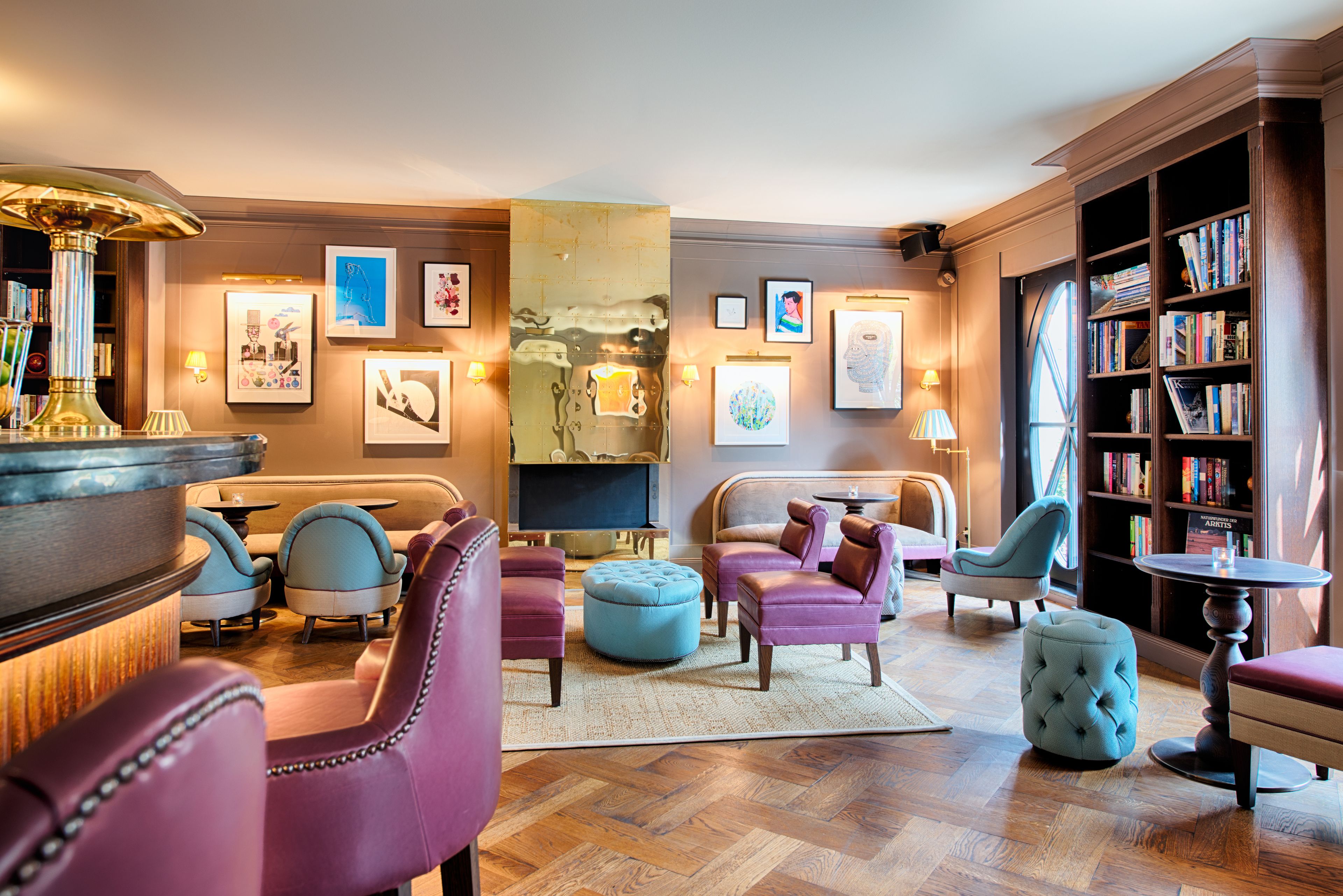 Un salon bien éclairé, doté de fauteuils confortables, d’une cheminée et d’une bibliothèque.