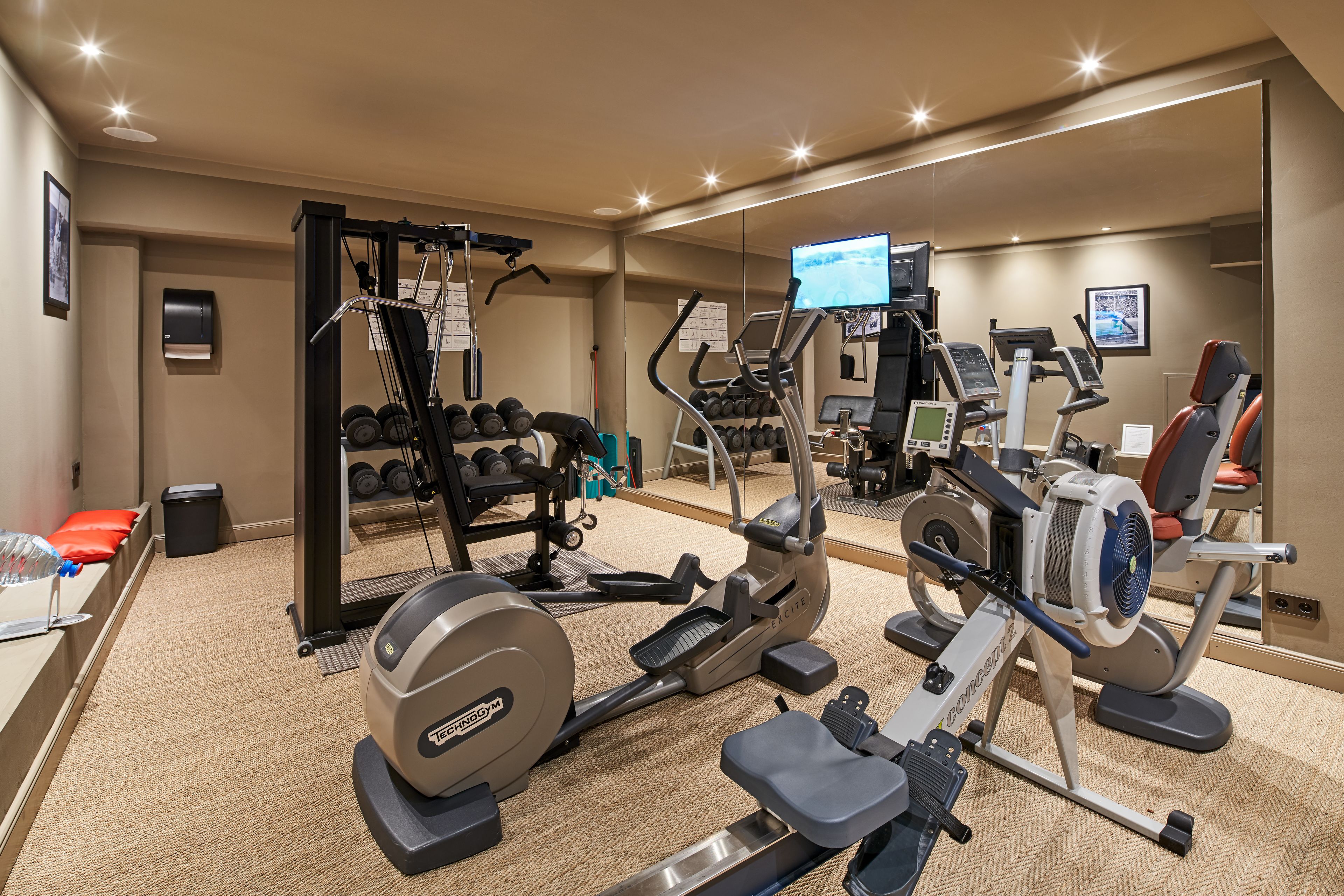 A gym with cardio machines, weightlifting equipment, and a mirror reflecting the space.