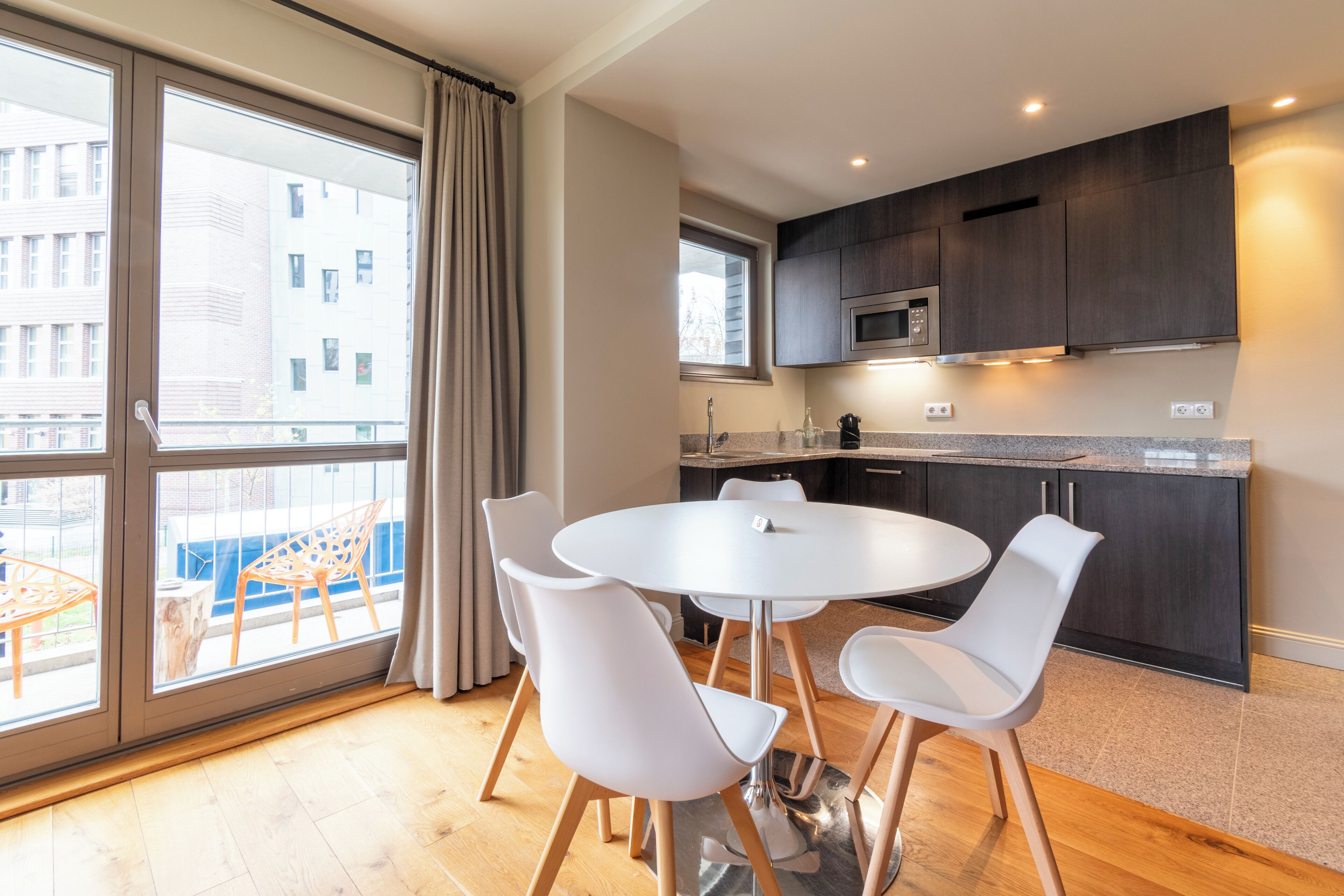 A modern kitchen with dark cabinets, a microwave, and a window overlooking a cityscape.